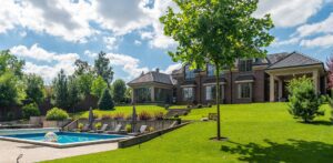 A large lawn with chairs and pool in the middle of it.